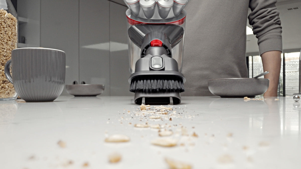 Miettes aspirées sur un plan de travail avec l'accessoire combiné du Dyson Car+Boat