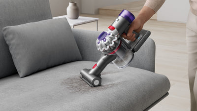 La mini brosse motorisée du Dyson Car+Boat nettoie un canapé en tissu